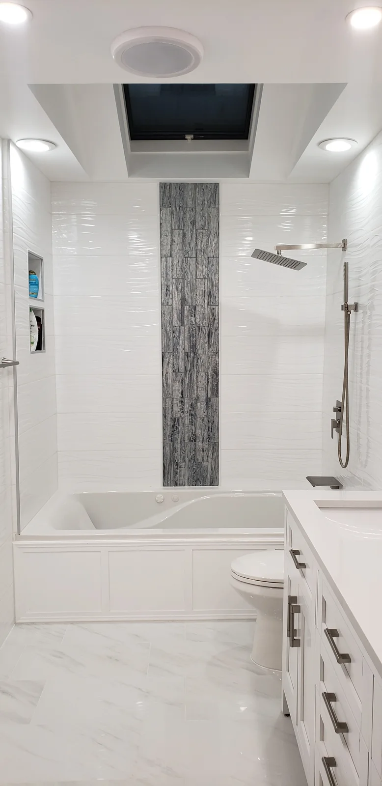 Finished Newburgh bathroom remodel with white tub-shower combo, gray accent tile wall, recessed lights, and white vanity