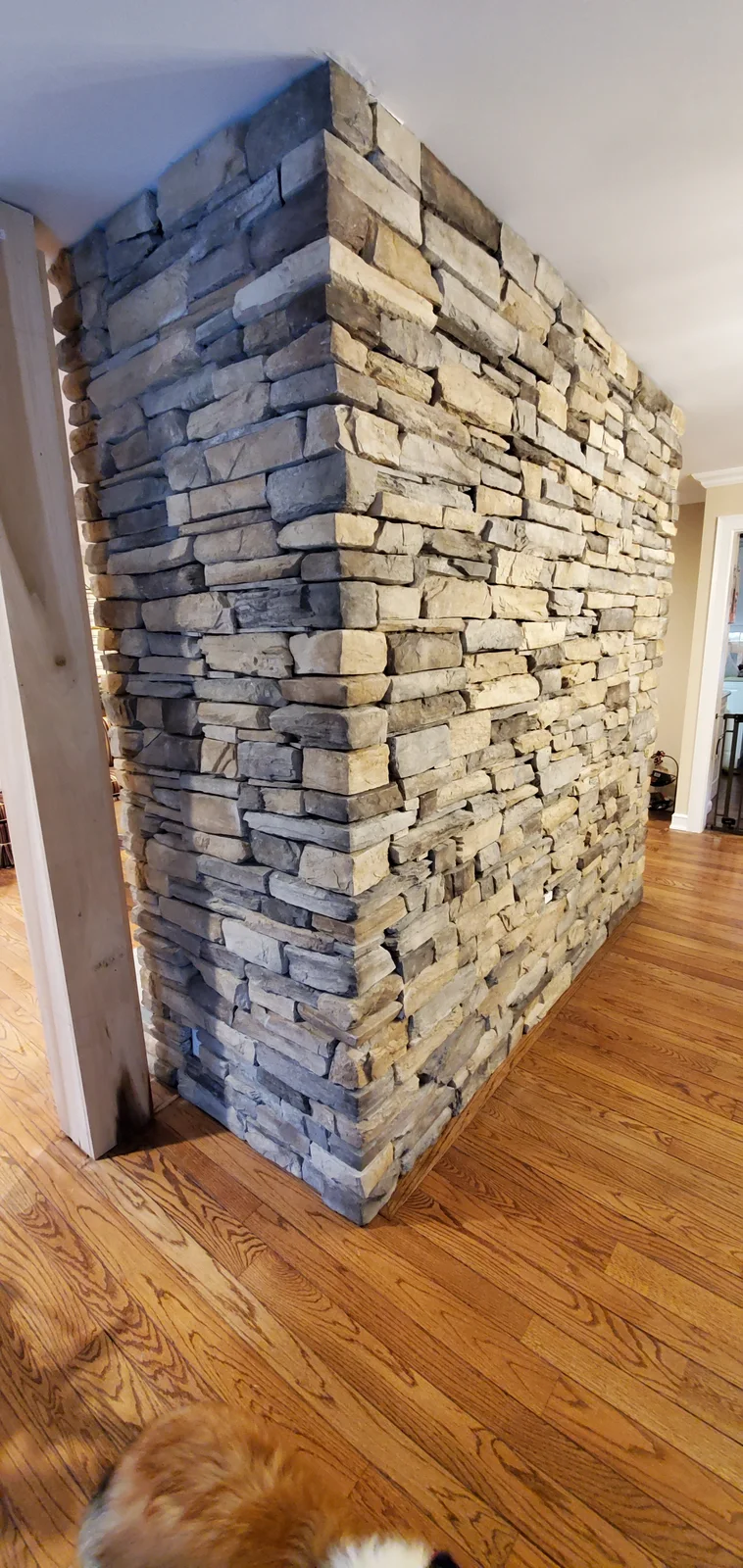 Finished Newburgh stone veneer fireplace with stacked stone surround, dark mantel, and raised hearth - photo 1