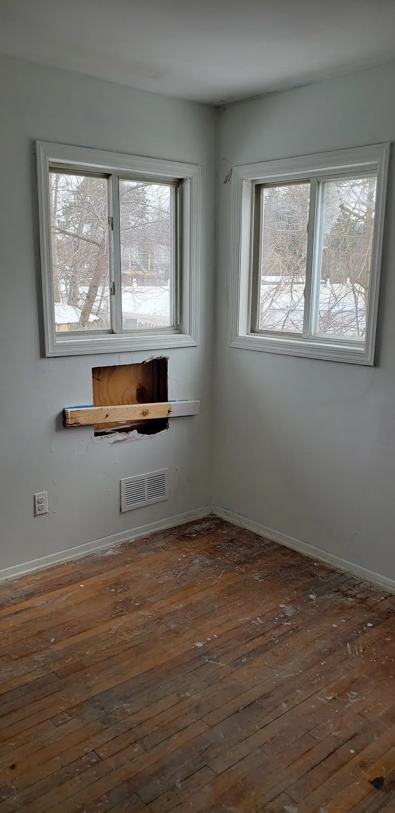 Finished rental property living room with teal walls, white trim, black entry door, large window, and refinished hardwood floor - photo 9