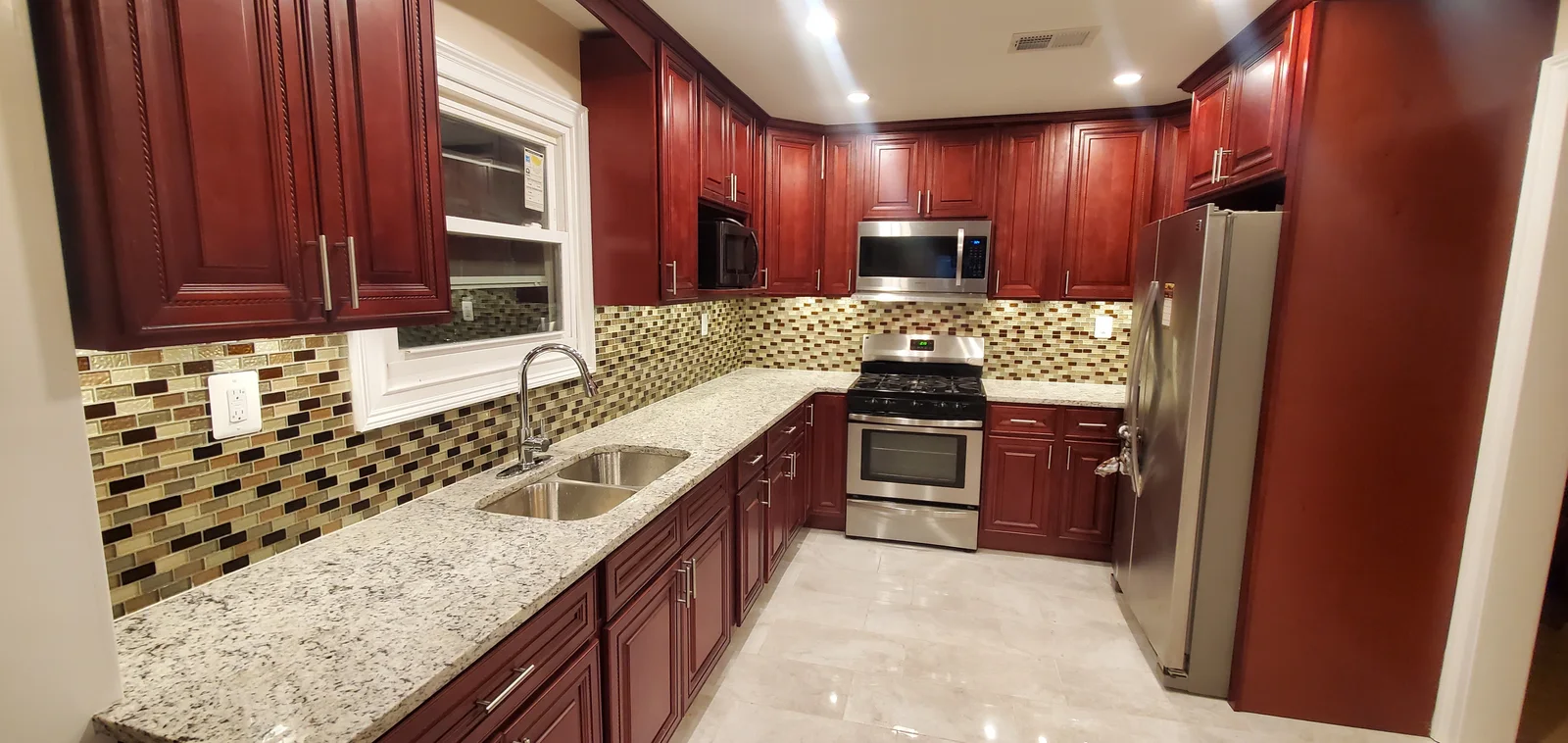 Finished kitchen remodel with cherry cabinets, granite countertops, mosaic backsplash, stainless appliances, and tile flooring
