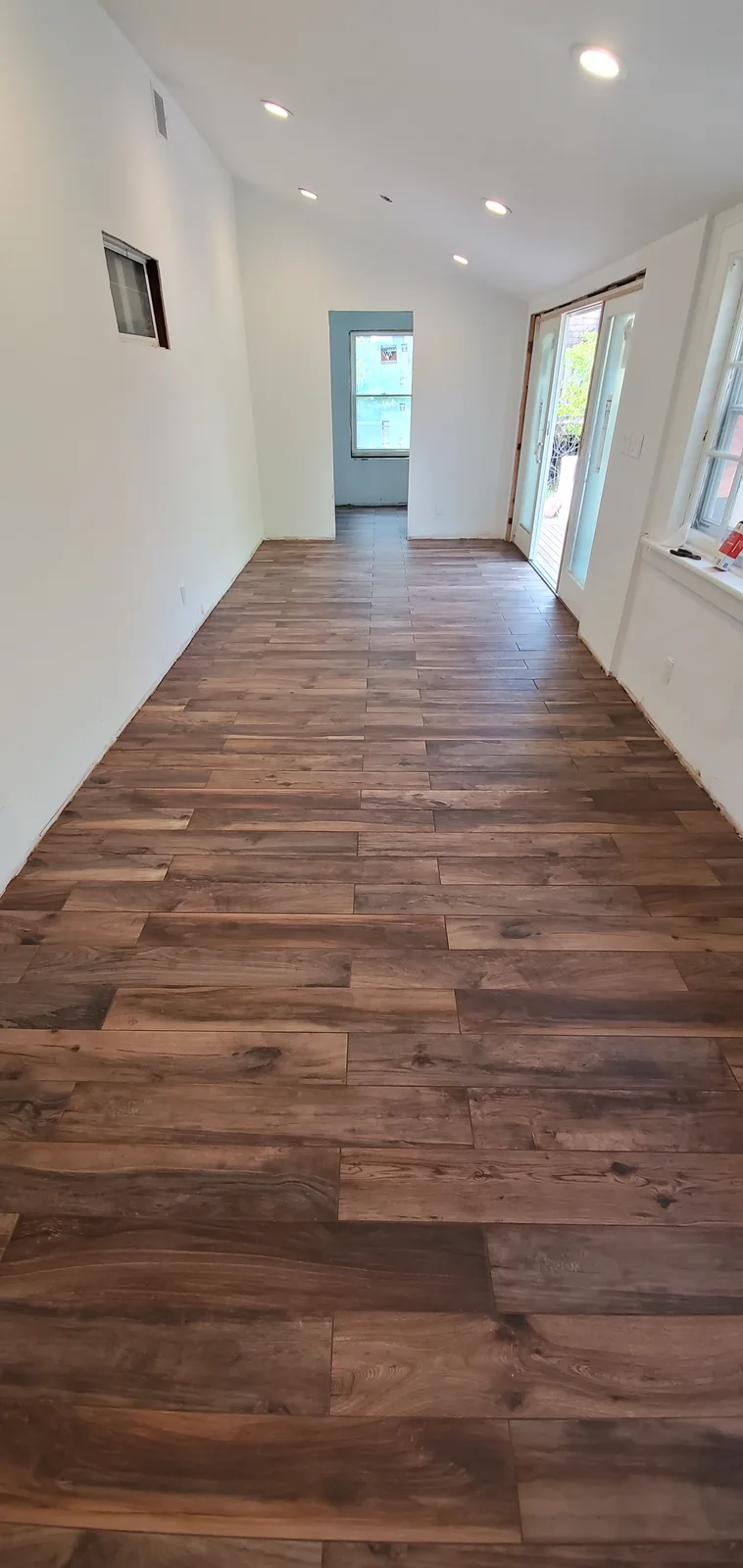 Finished wood-look tile flooring installed throughout a bright remodeled interior - photo 1